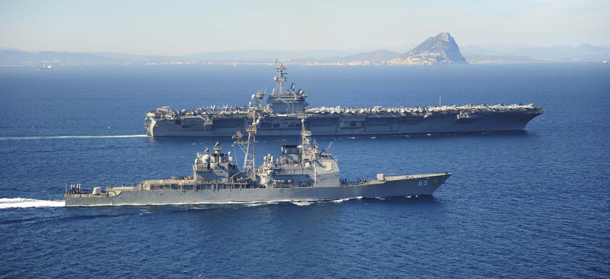 Naval warship escorting commercial cargo vessel in the Red Sea amid rising maritime tensions