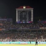 International cricket teams competing in a high-pressure T20 World Cup match under stadium floodlights.