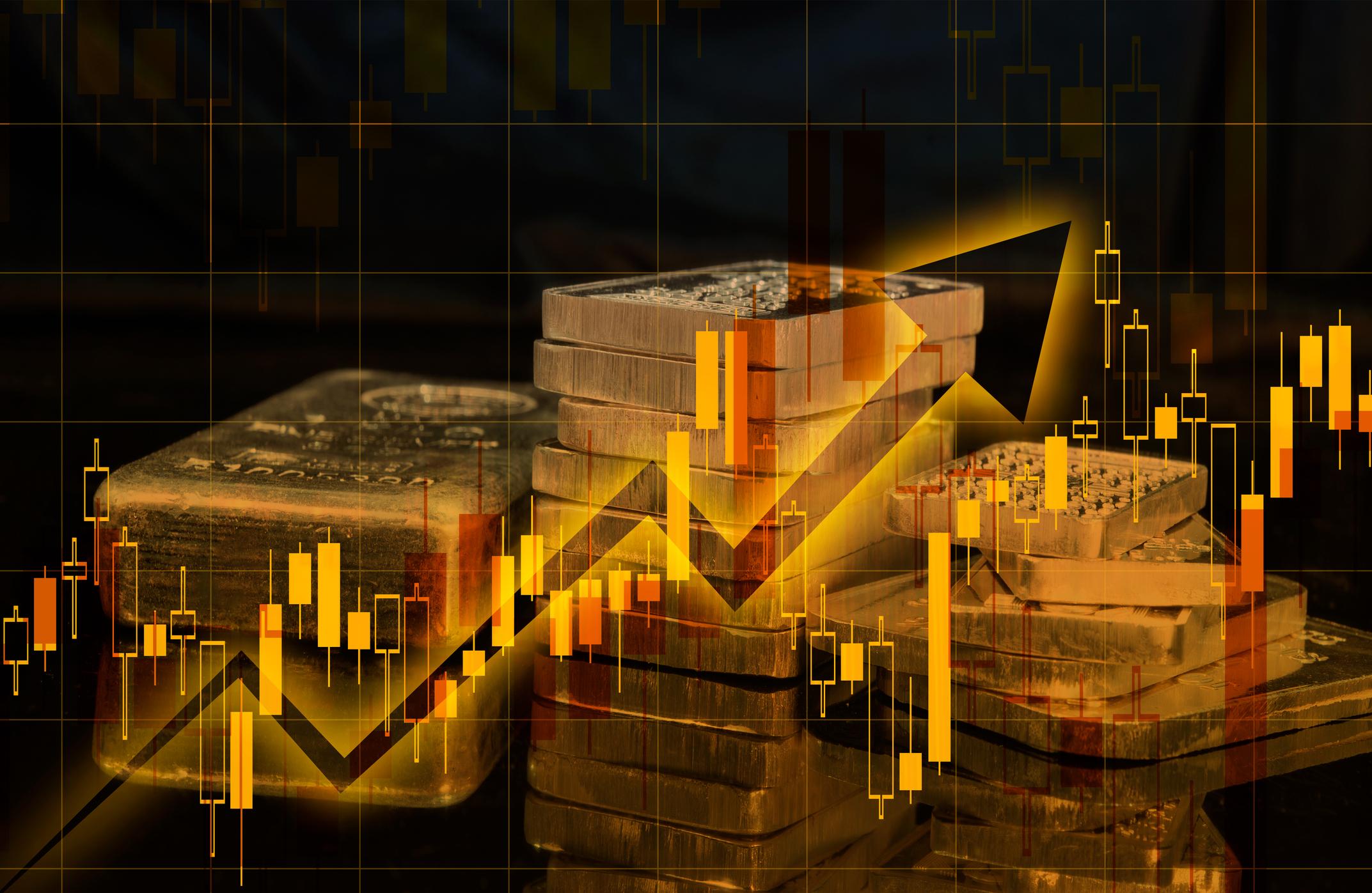 Gold and silver bars placed over a falling financial market chart.